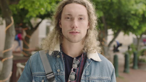 portrait of attractive young blonde male student looking serious at camera confident wearing cool denim fashion in urban city street