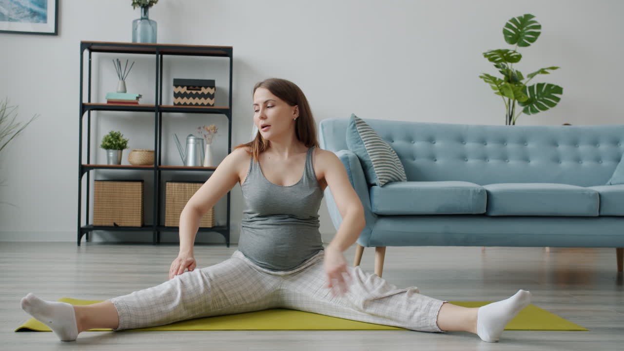 беременная женщина растягивается дома