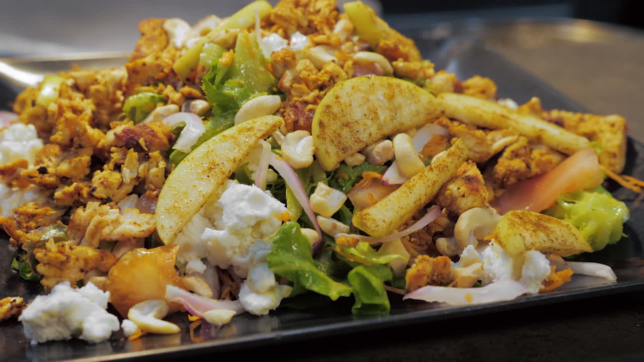 ensalada nutritiva apilada con manzanas, pollo, queso de cabra, anacardos, control deslizante en cámara lenta.
