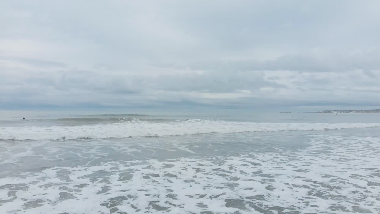 멀리 서퍼들이 있는 해변의 화이트 워터와 파도