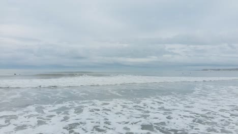white water and waves on the beach with surfers in the distance