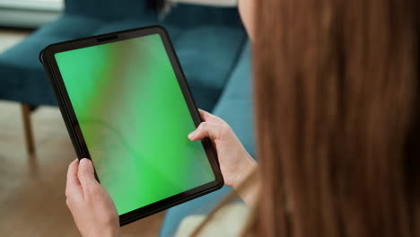mujer desplazándose en la tableta en casa