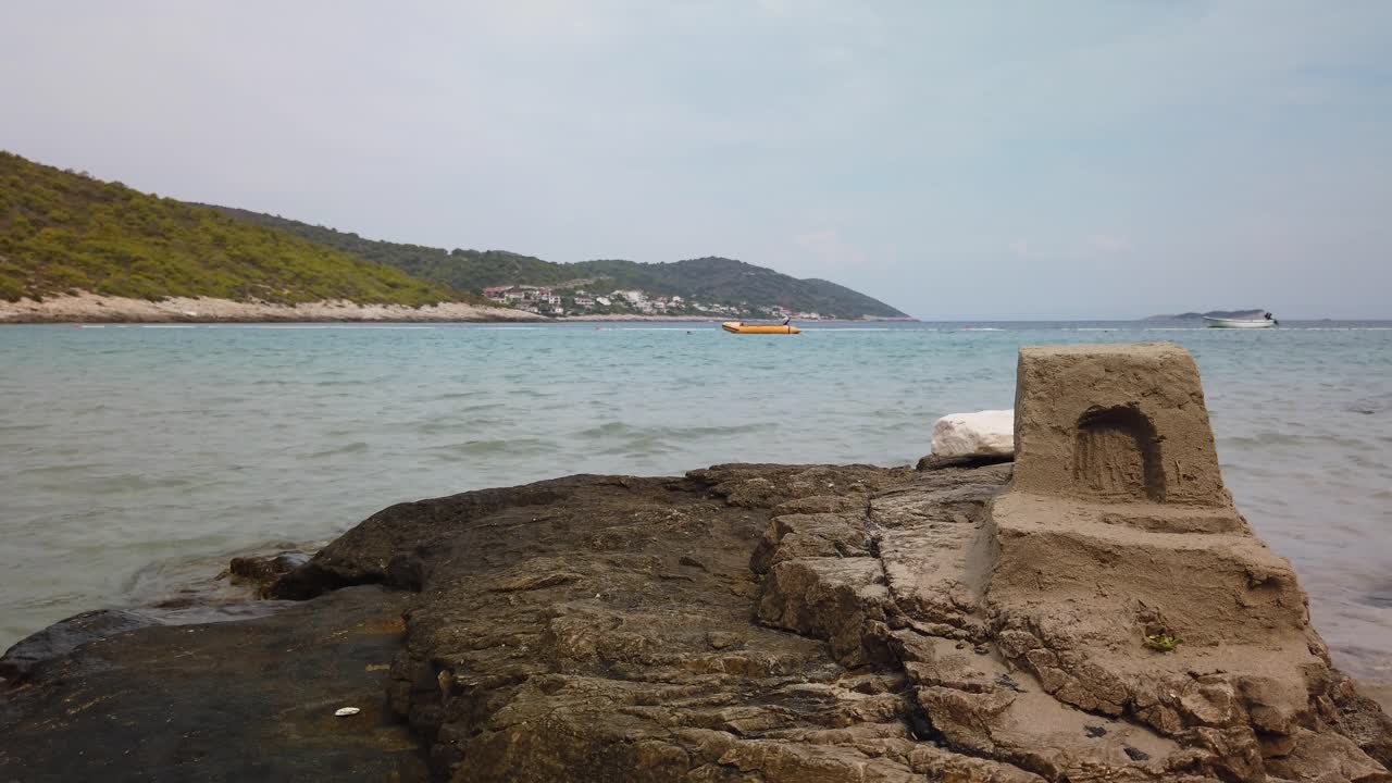 해변의 큰 바위 위에 작은 모래 성이 있는 자글라브 해변의 전망