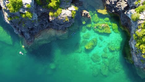 a few people swimming in a small rocky cove in the georgian bay, ontario, canada