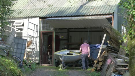 man pulling a small boat from a shed