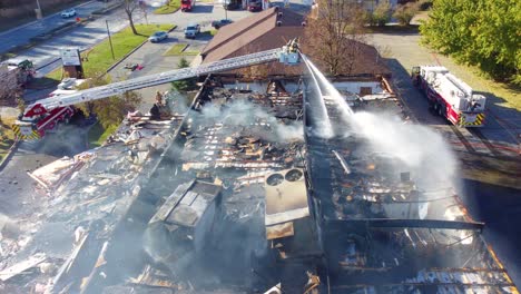 Fire-Fighter-Suspended-High-on-Ladder-Spraying-Down-Building-on-Fire