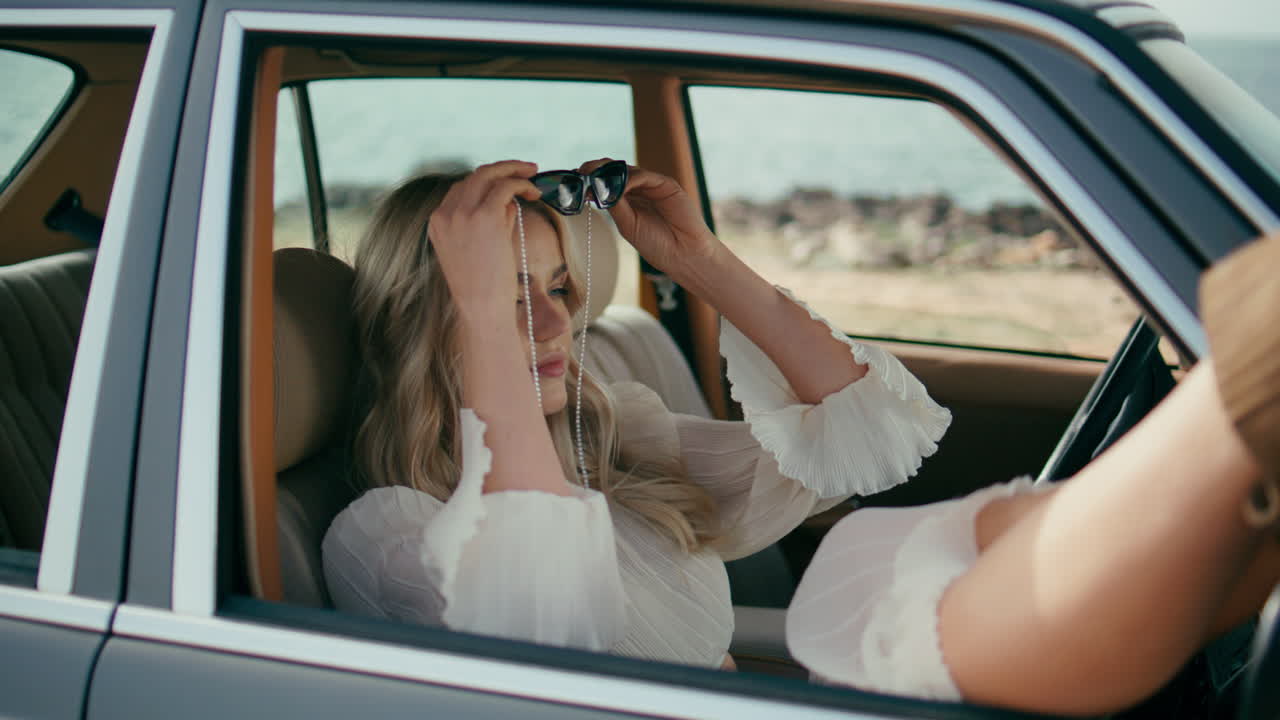 una mujer hermosa pasajera relajándose en un coche retro poniendo las piernas en un primer plano de la ventana abierta