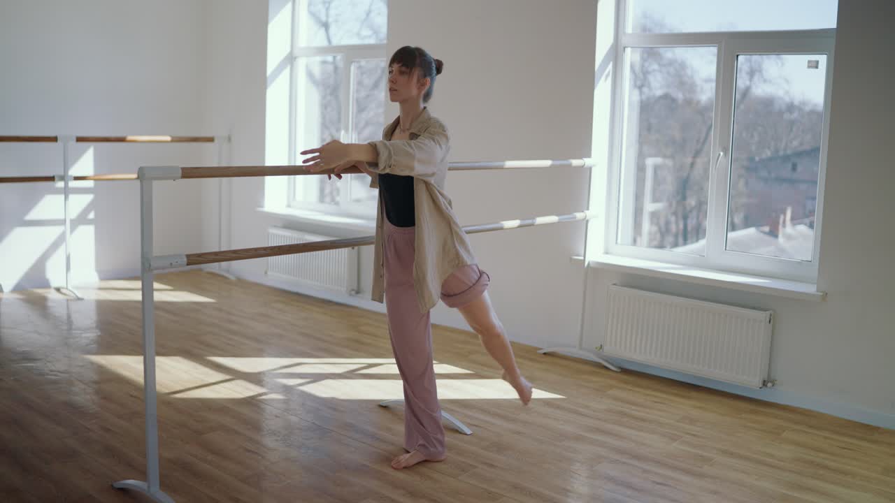 Ballet dancer practicing at the barre in a studio