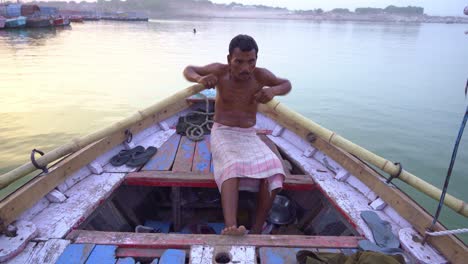 traditional boatman rowing on an indian river at dawn or dusk