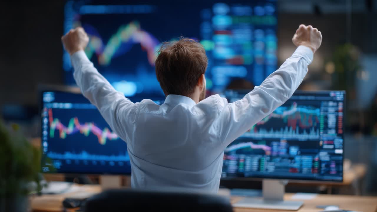 Excited Trader Celebrates Success After Monitoring Market Trends on Dual Computer Screens Displaying Cryptocurrency and Stock Data in a Modern Office Environment