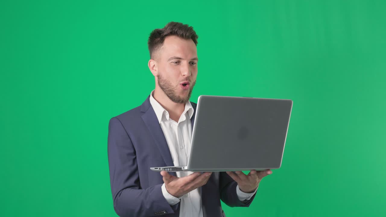 retrato de un hombre de negocios en un traje de negocios atrapa una computadora portátil sonriendo y mira a la cámara en una pantalla verde, llave de cromo