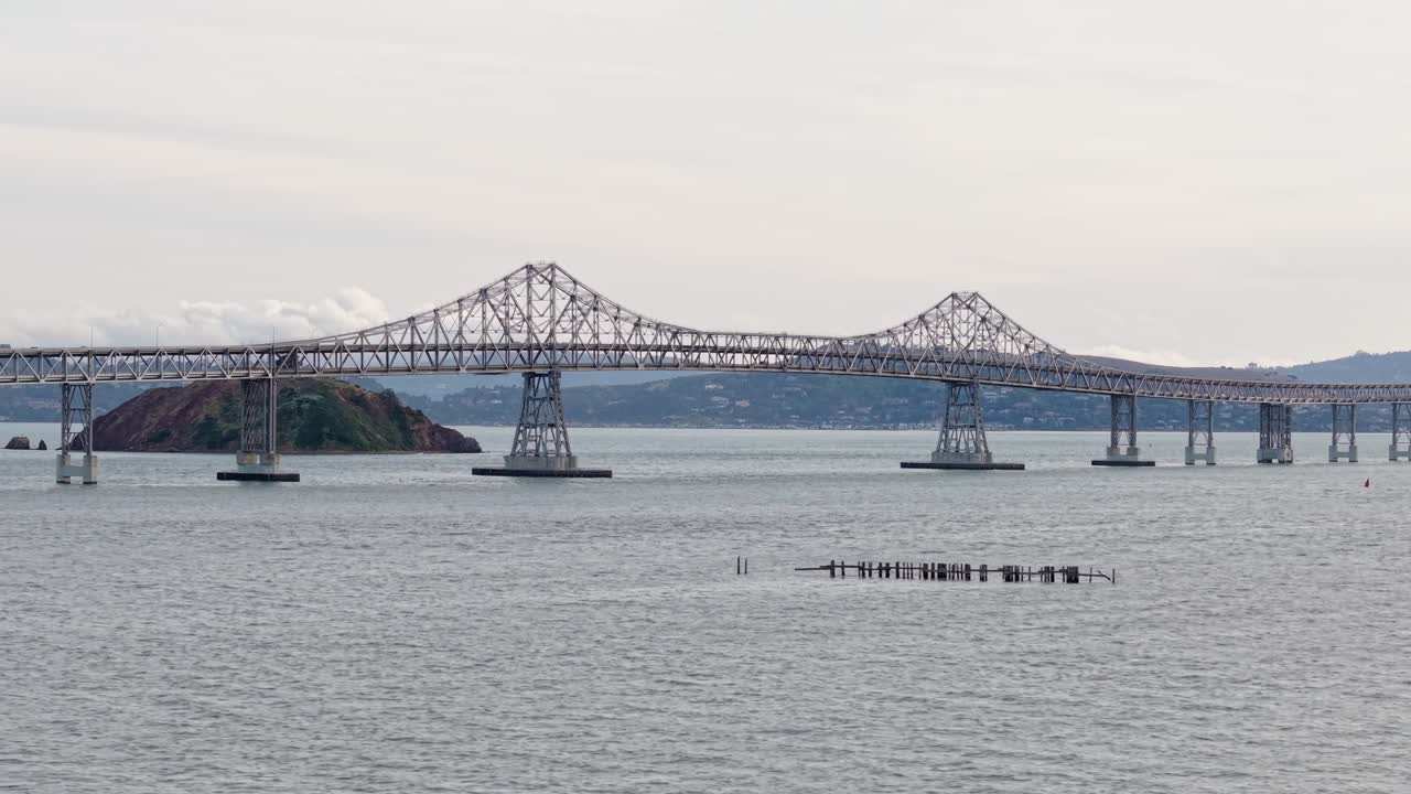 The bridge curves through the air from Richmond to San Rafael as seen from above, framed by soft clouds and peaceful bay currents.