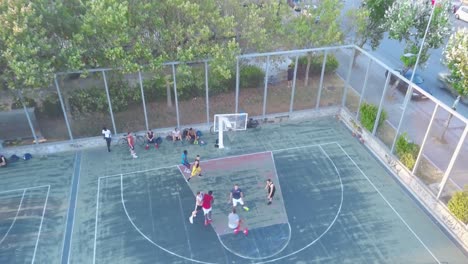 players during an outdoor basketball game in thessaloniki, greece. basketball court near the road - aerial drone