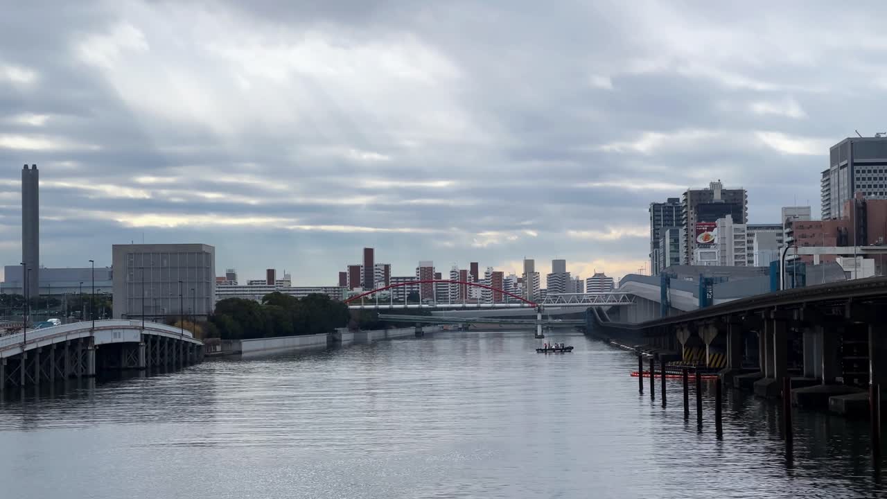 A serene view of Tokyo cityscape with a river, bridges, and cloudy sky