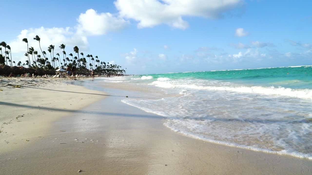 Caribbean sea is gently reaching the beach. Waves move back and forward to the beach