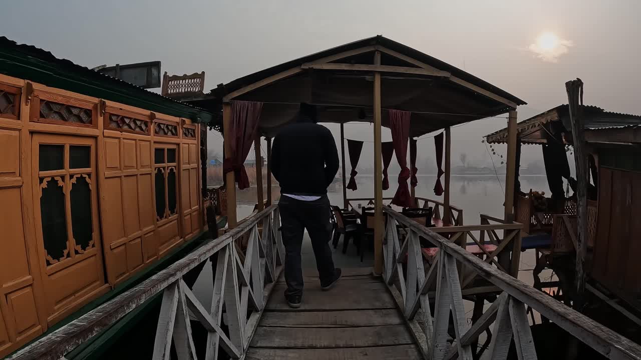 Person walking on wooden bridge with sun and houseboat at dal lake, srinagar, Jammu and Kashmir, Delhi, india. day time, follow short, 4k.