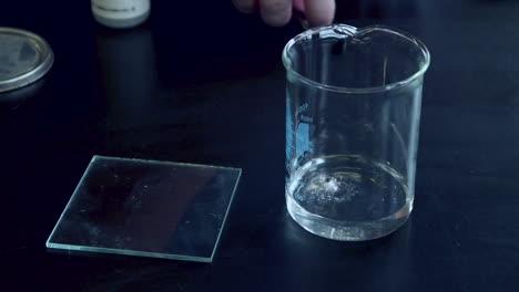 a small piece of sodium metal being added to a glass beaker with water and reacts vigorously to produce flamable hydrogen gas that is lit by a burning splint