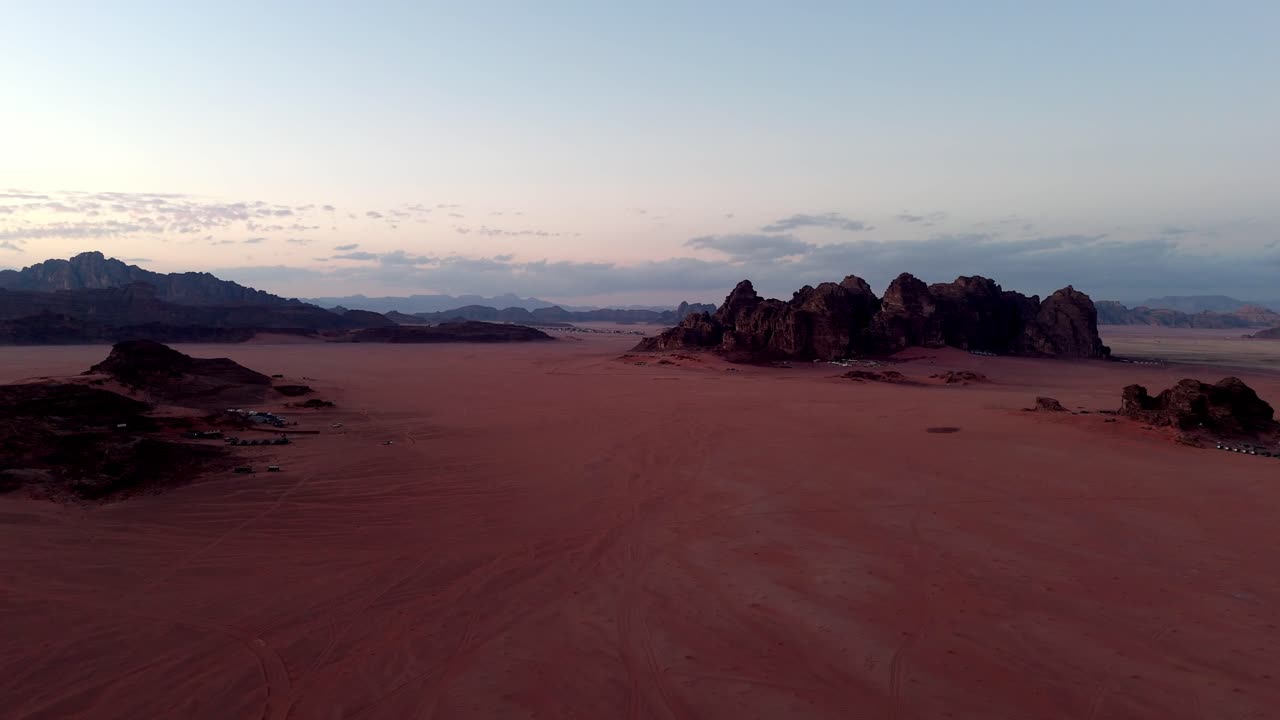 Sequenza di drone che scivola silenziosa attraverso le valli di Wadi Rum dopo il tramonto, ripresa durante l'ora blu in Giordania