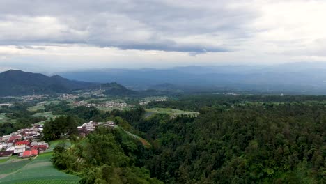 Rainy-clouds-above-Indonesia-forest,-mountains-and-plantations,-aerial-drone-view