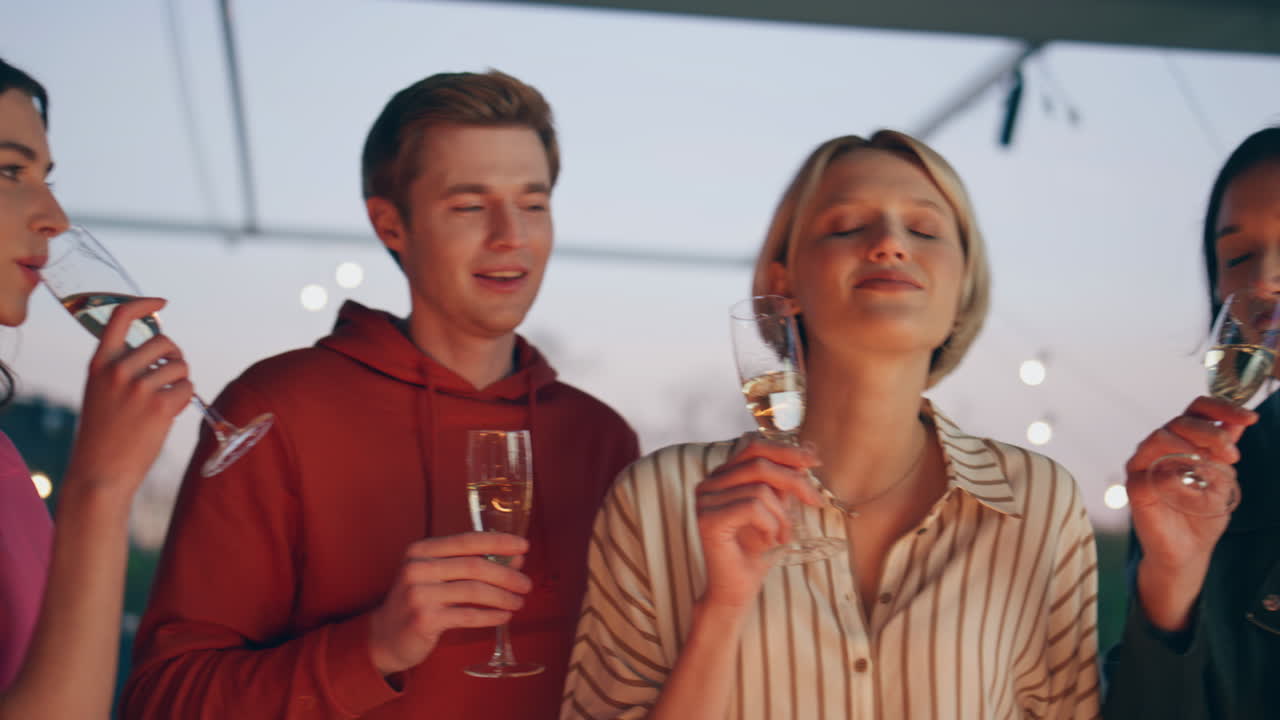 감성적인 학생들이 해가 지는 바 테라스 근접에서 프로세코를 걱거리는 사람들 파티