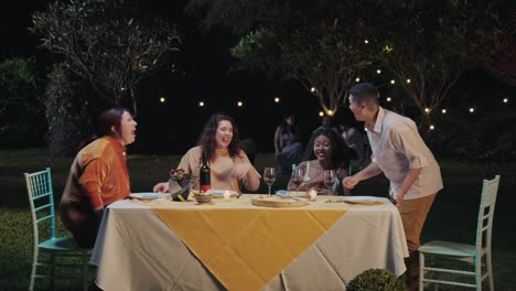 Friends enjoying an outdoor dinner party at night with string lights