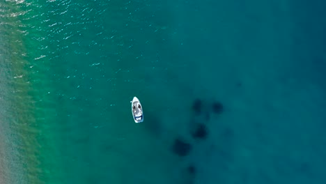 Boot-Schwimmt-Auf-Klarem-Türkisfarbenem-Meerwasser-In-Der-Nähe-Des-Unberührten-Strandes,-Wo-Sich-Die-Menschen-Im-Mittelmeer-Sonnen