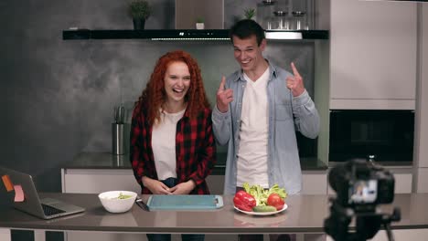 young couple in casual cooking together and recording video food blog on camera in the loft, grey kitchen at home. excited