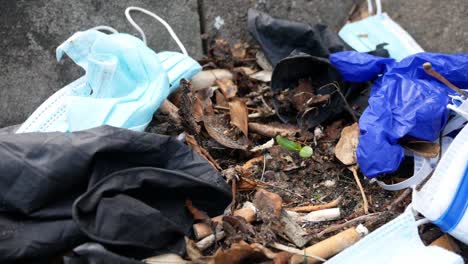 dirty disposable corona virus face masks and latex gloves among cigarette rubbish on street curb