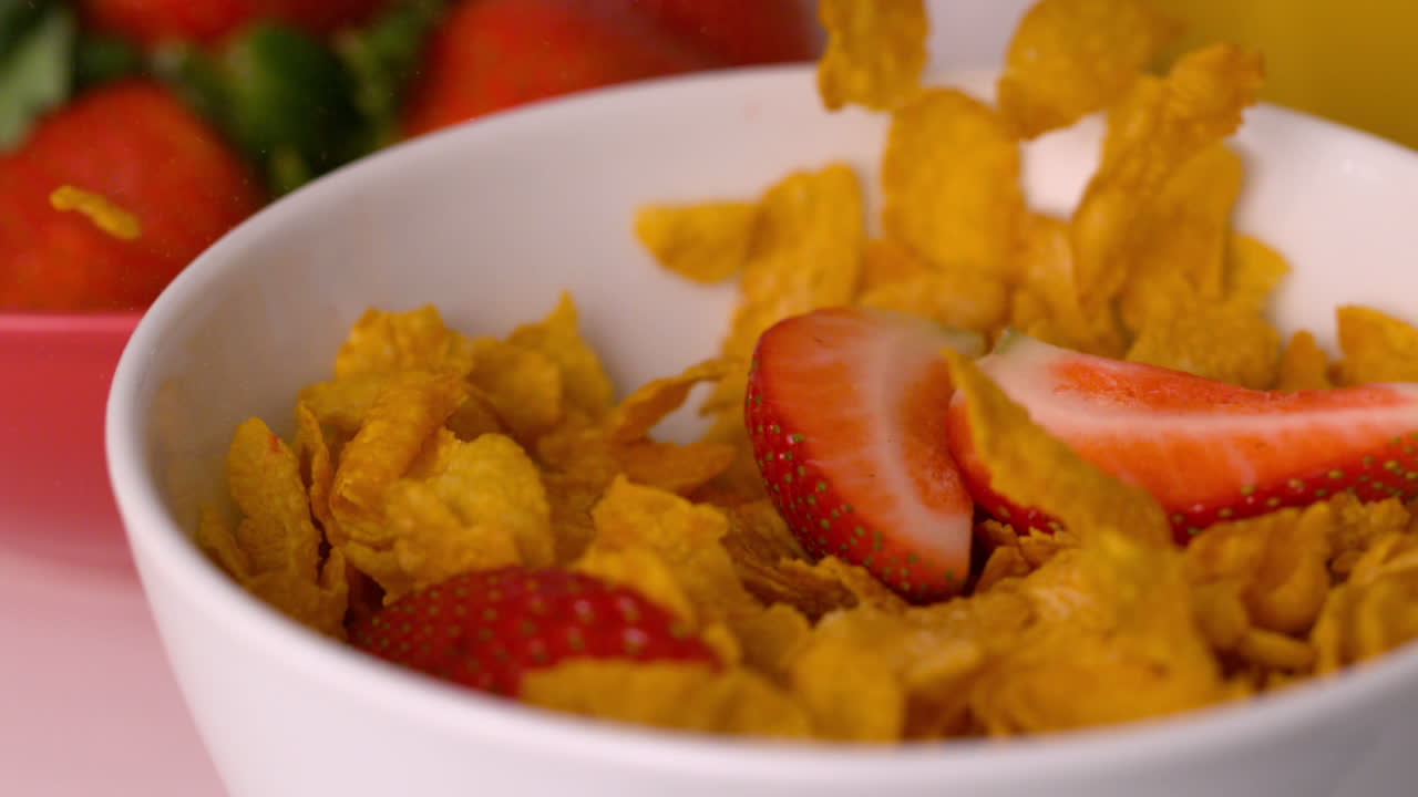 Fragole che si versano in una ciotola di cereali al tavolo della colazione