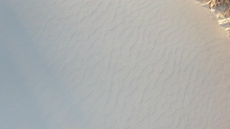 Revealing-view-of-a-frozen-lake-and-skiers-with-sunset-and-mountains-in-the-background