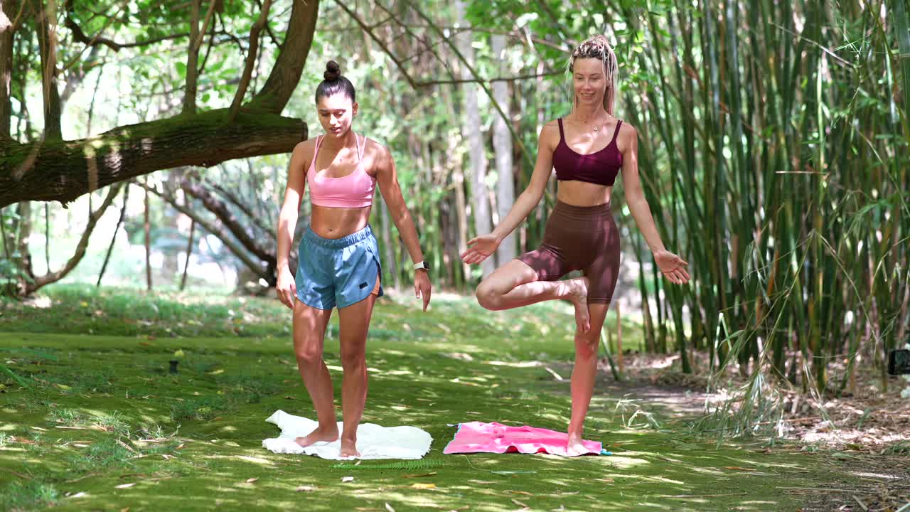 Two women doing yoga in a bamboo forest