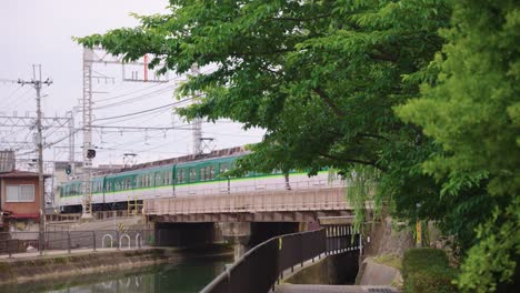 kyoto train passing over bridge in fushimi ward, japan