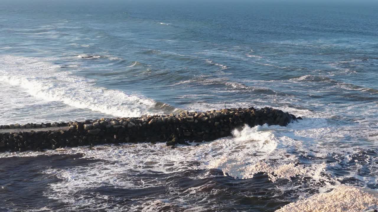 Dynamic ocean waves crash against a rocky jetty under clear skies at Brunswick Heads, NSW. Captured in natural daylight
