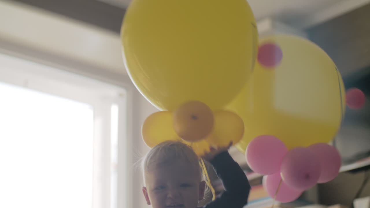 아기자루에 풍선을 가진 장난스러운 아기 소녀