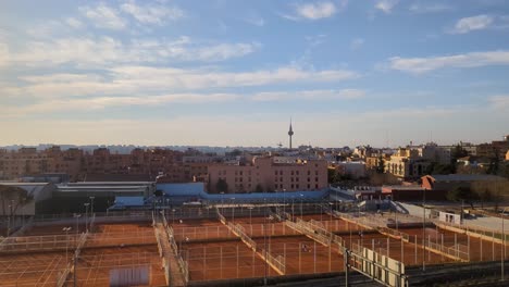 Von-Oben-Nach-Unten-Luftaufnahme-Der-Skyline-Der-Stadt-Madrid-Am-Frühen-Morgen-Mit-Blauem-Himmel-Und-Tennisplatz-Im-Vordergrund