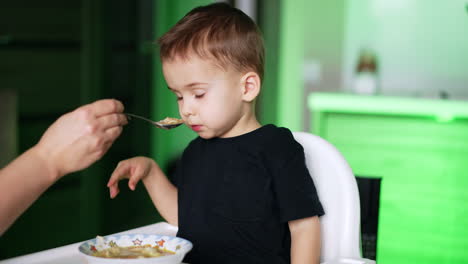 cute child hate eating soup. small boy not want eating.