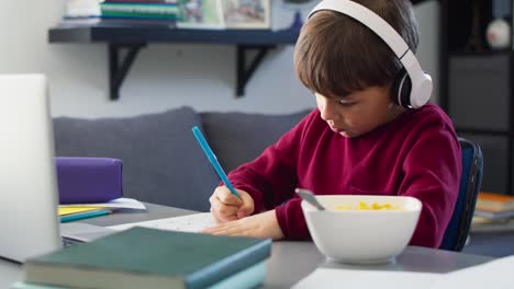 handheld video of boy doing homework during breakfast