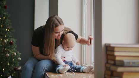 madre con bebé sentada en la ventana y jugando