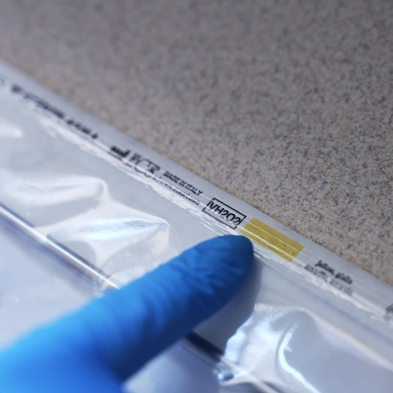 Medic gloved hand touching the plastic bag with metal instrument inside. Close up. Sterilization of tools in equipment. Top view