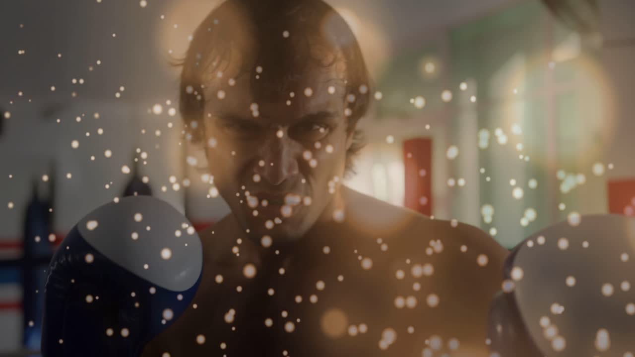 Camera closing in, male boxer keeping guard and practicing jabs in boxing ring, particles drifting