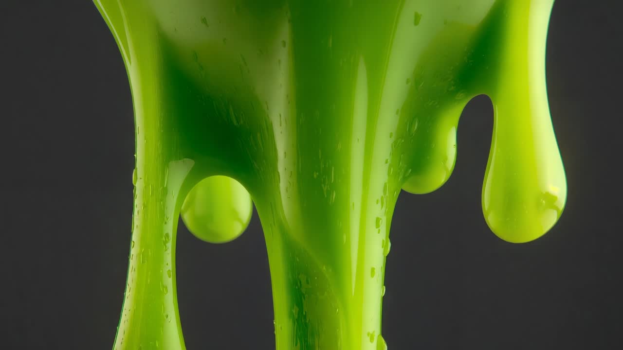 Gravity pulling bright green liquid into drips, releasing droplet, showing fluid behavior in studio