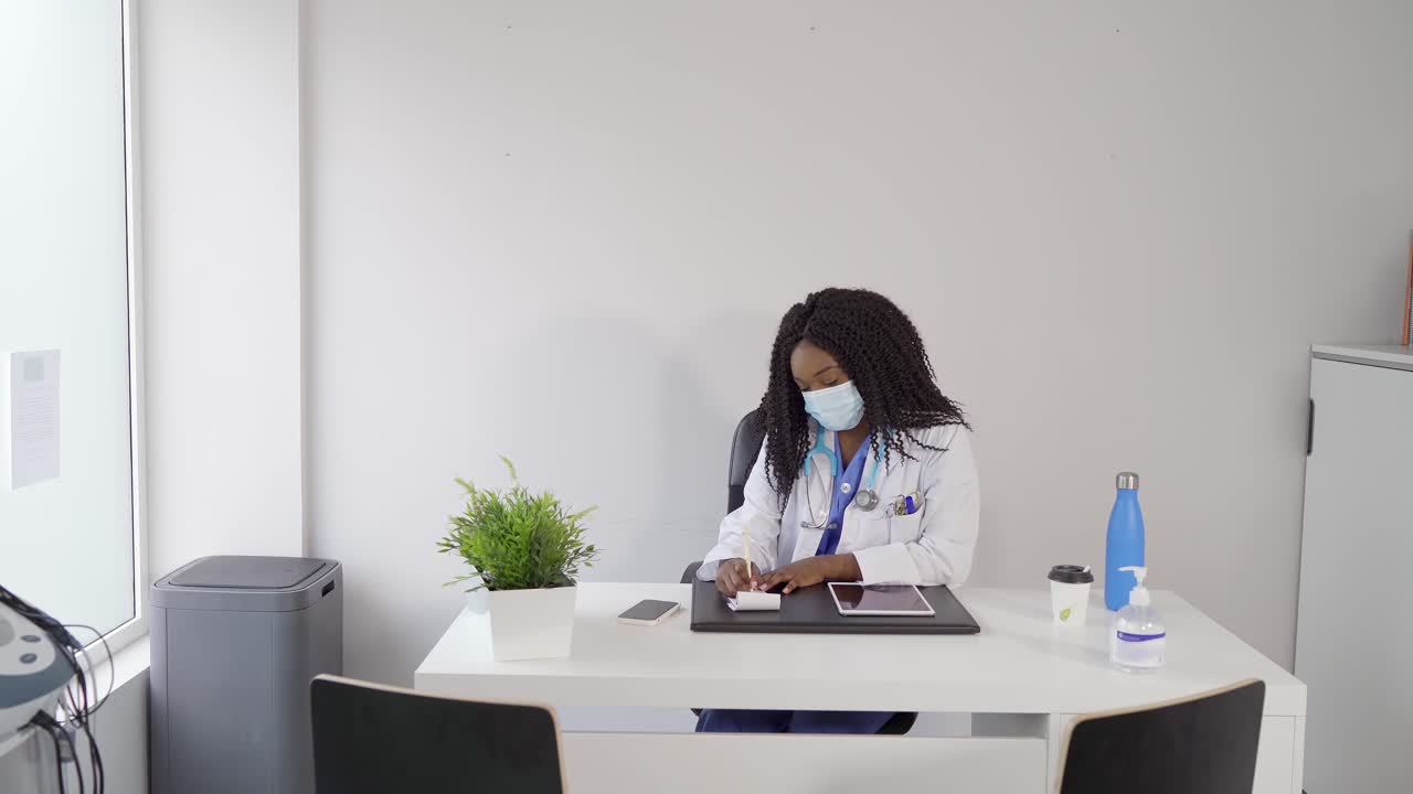Smiling African American doctor writing in notebook