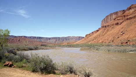 pan a la izquierda amplia fotografía del paisaje de un impresionante pico de roca de piedra arenisca naranja con el río colorado por debajo cerca de moab, utah en una cálida y soleada mañana de primavera