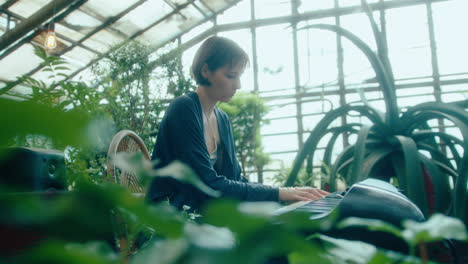 female musician playing synthesizer in greenhouse of botanical garden