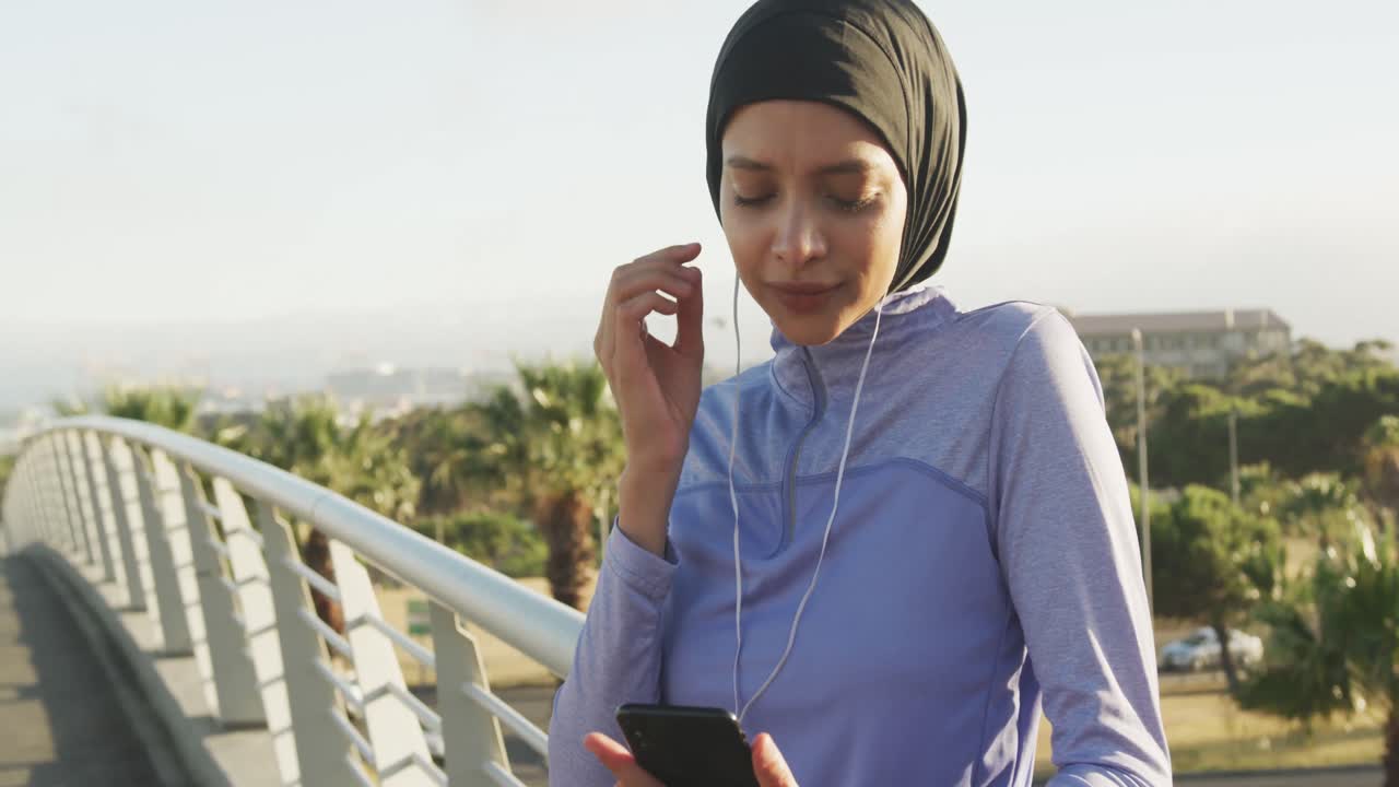 Woman wearing hijab listening music outside