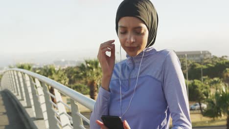 mujer con hijab escuchando música afuera