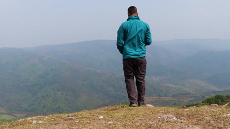 hombre solo en la roca de la montaña con fondo de niebla blanca desde un ángulo plano