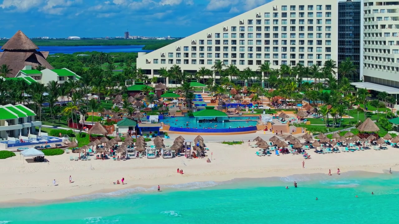 Veduta aerea di un resort in stile piramidale con piscine e giardini lussureggianti lungo la spiaggia della Zona Hotelera di Cancun, Quintana Roo, Messico.
