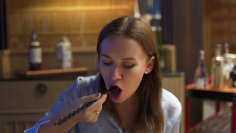 una toma estática de una joven hermosa niña marrón comiendo comida con la ayuda de un palillo de madera en su casa