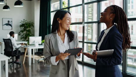two businesswomen collaborating and discussing work in a modern office